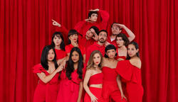 Group of people dressed in red against a red curtain.