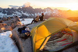 Tent with campers on the side of a mountain in the snow.