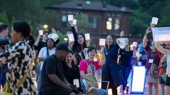 A group of RISD alumni hold up paper lanterns