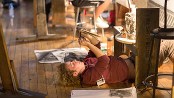 Freshman drawing in sketchbook lying on the floor