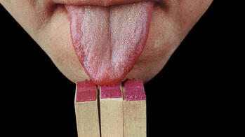 close-up photo of a person touching their tongue to matches