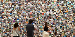 Three people stand facing a wall of hundreds of colorful photographs