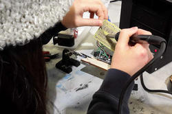 a pair of hands manipulating the wires on a circuit board at a workstation