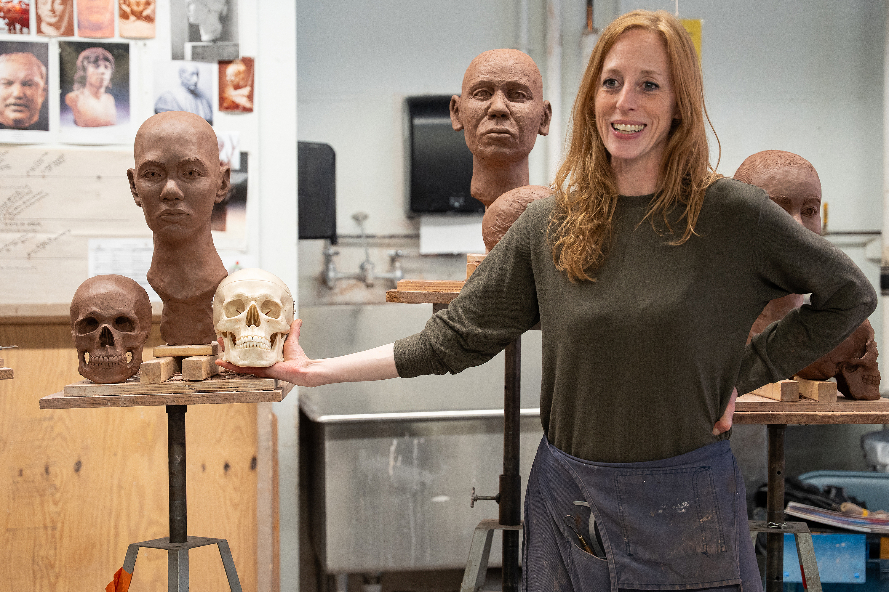 Ann Hirsch holds a human skull next to the one created in clay by a student