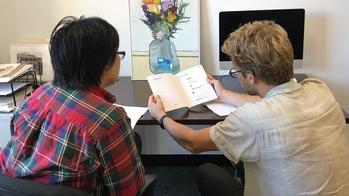 Two people are engaging in a peer tutoring session at a desk in the Center for Arts & Language.