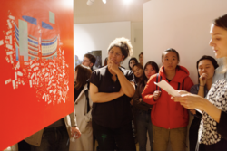 people focus on a red poster hanging in the middle of an art gallery space