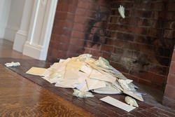 many pieces of a white, paper-like material messily piled in front of a red brick fireplace